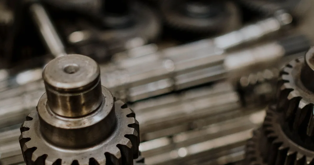 Steel gears stacked on a shaft in a workshop, parts where case hardening vs through hardening is chosen